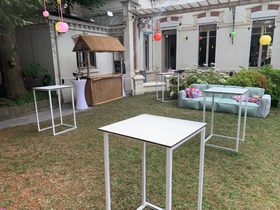 Mange-debout blancs et buvette en bois dans le jardin, devant la façade de la maison