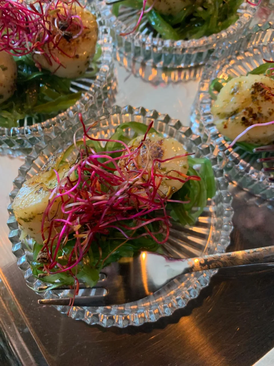 Coupelles en verre garnies de salade, de noix de Saint-Jacques et de pousses roses