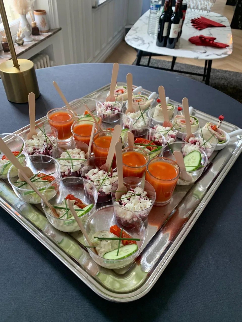 Plateau argenté de verrines colorées de gaspacho et de crudités sur une table de réception