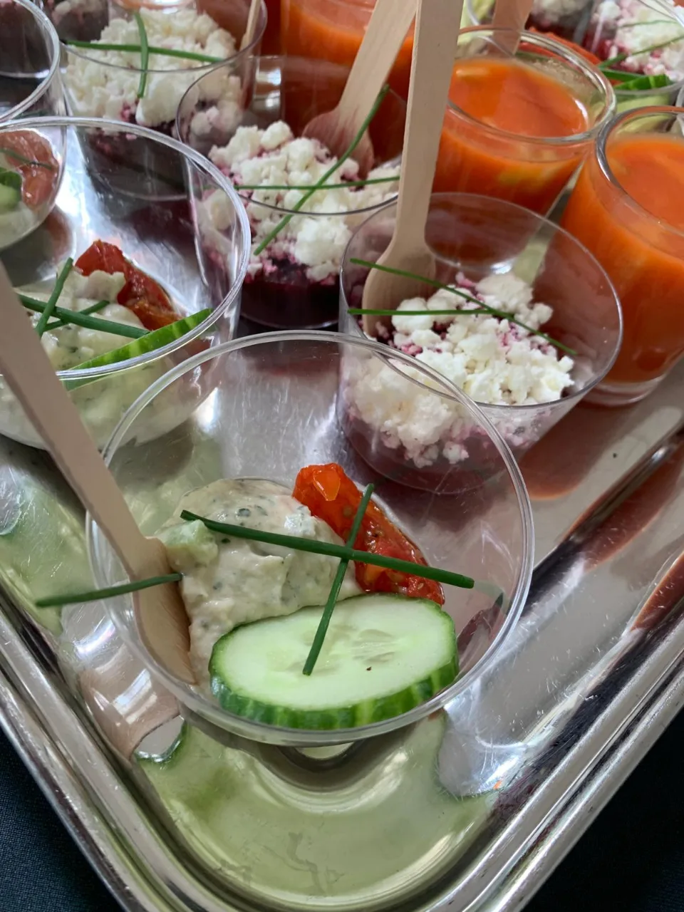 Verrines de gaspacho et de fromage frais au concombre servies avec des cuillères en bois