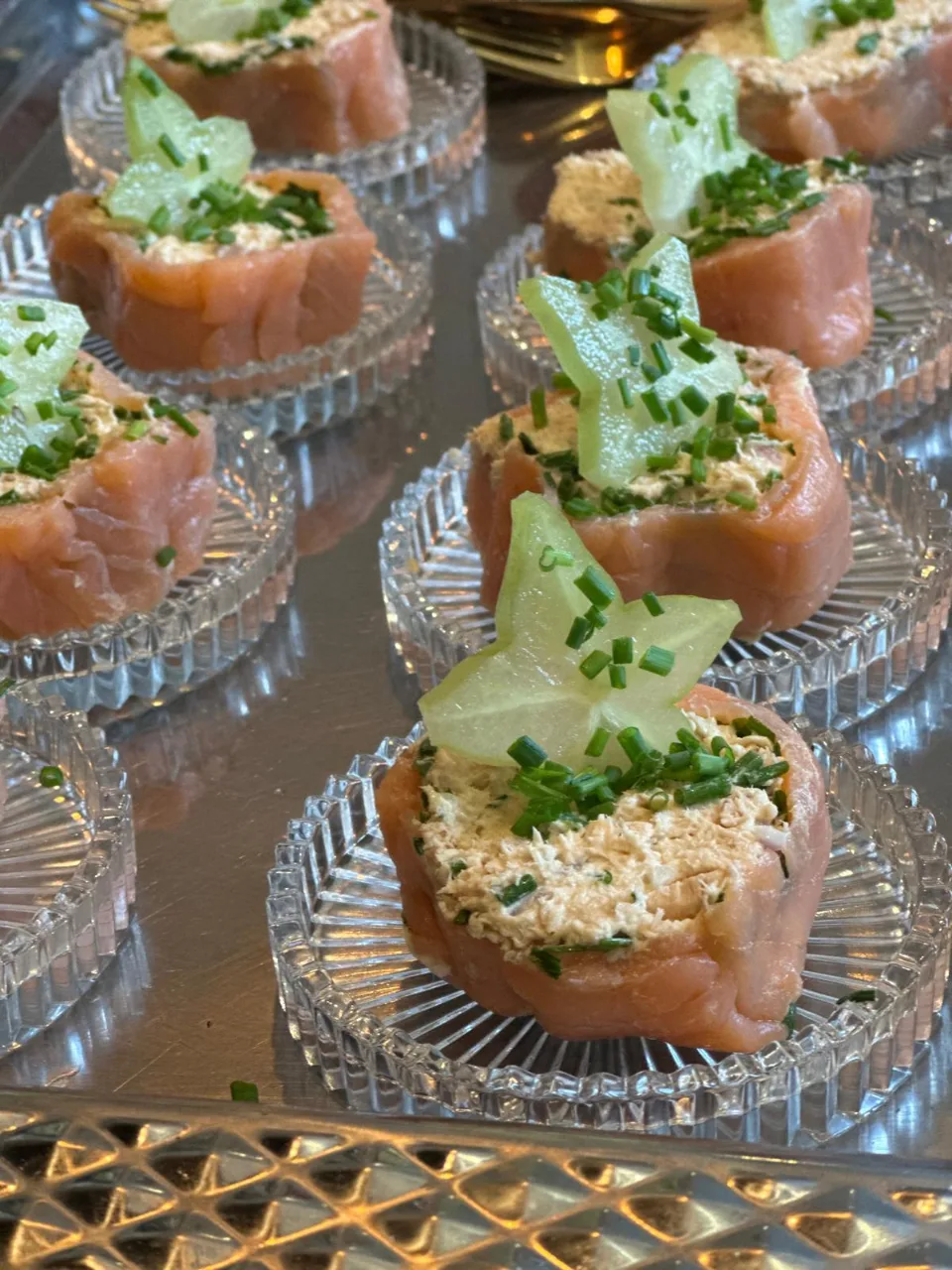 Verrines de saumon fumé garnies de fromage frais, de ciboulette et d'une étoile de concombre sur plateau