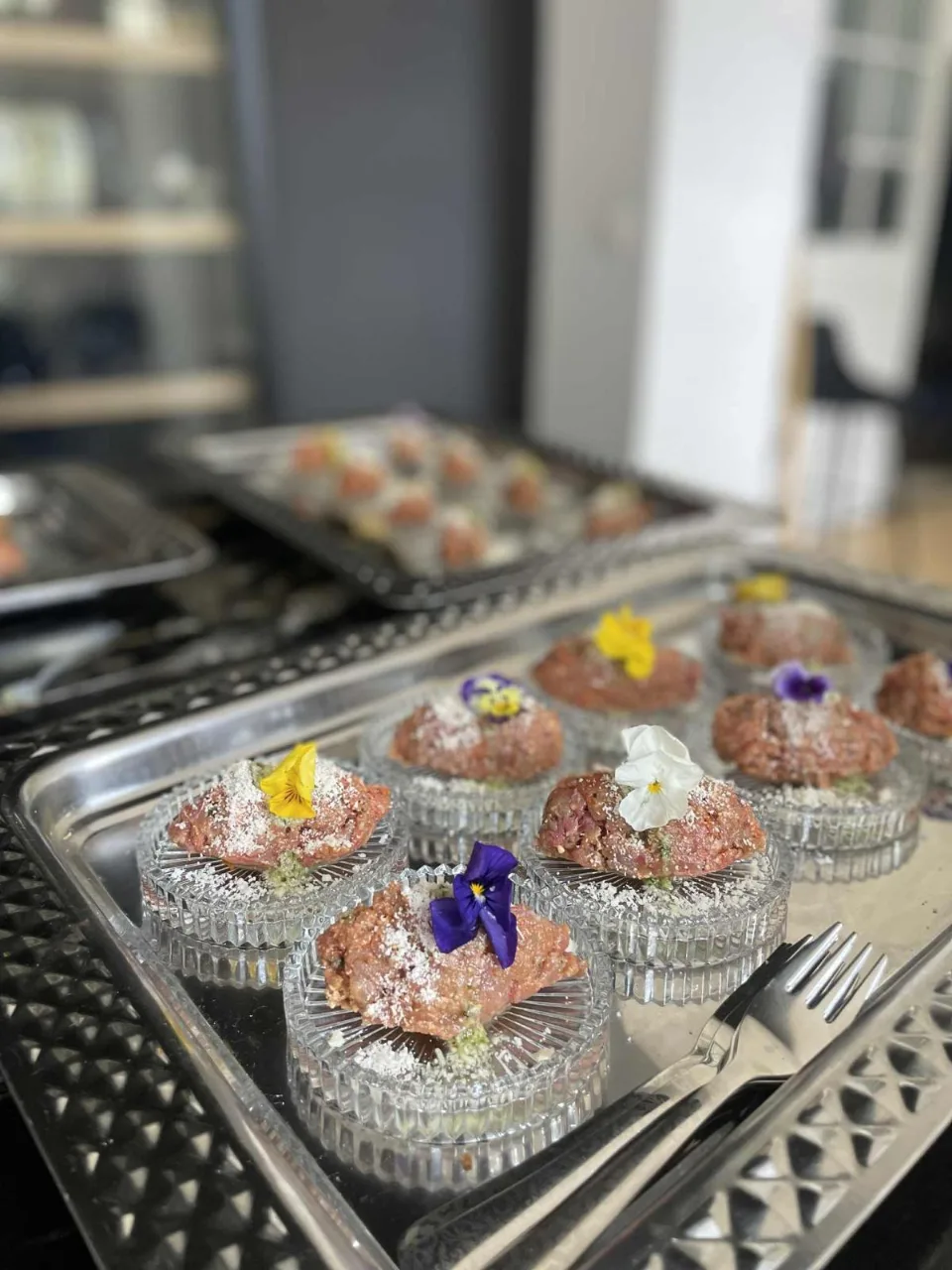 Coupelles en verre garnies de tartare décoré de fleurs comestibles, sur un plateau argenté