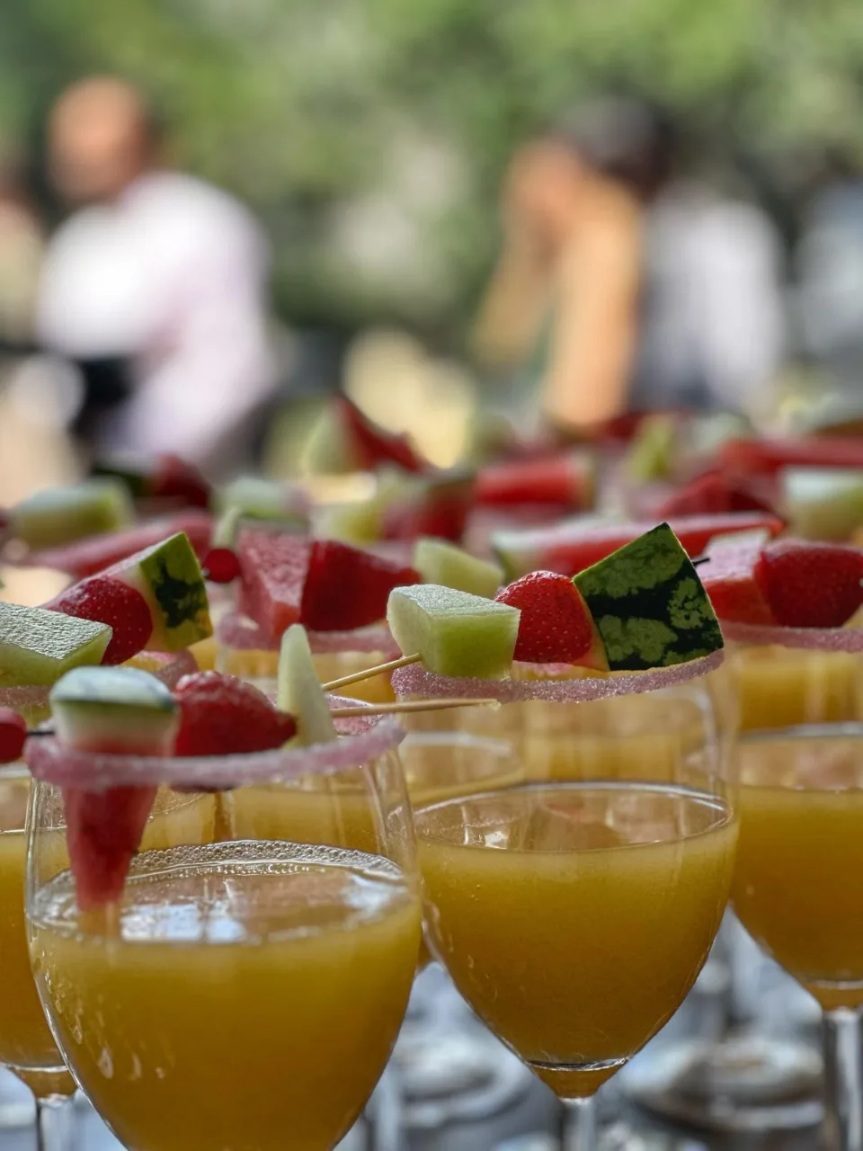 Verres de jus d'orange frais avec brochettes de pastèque et de fruits sur le bord du verre